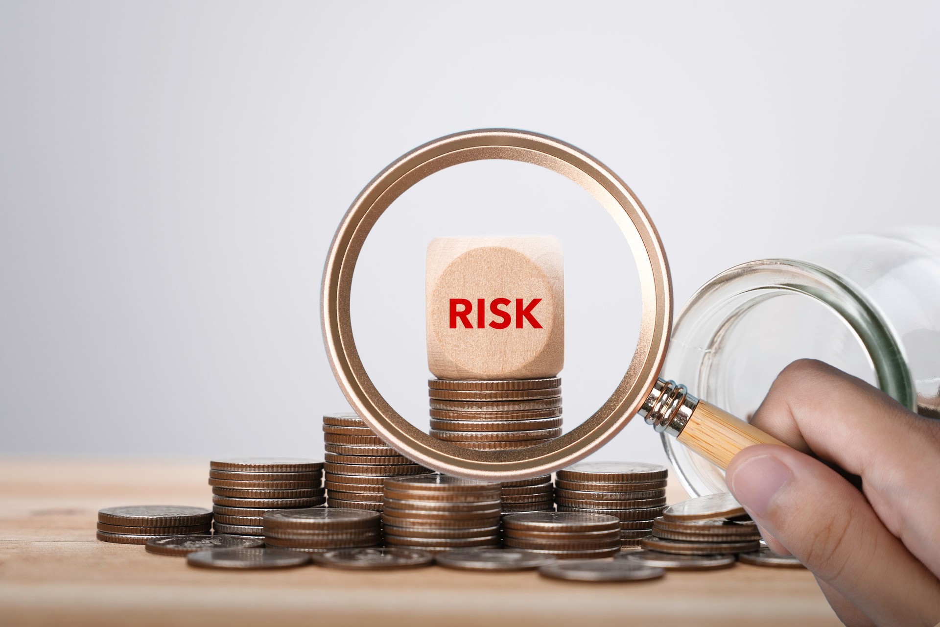 Risk management of finance and investment. magnifier glass focus Risk word on wooden block cube and Heap of coins money for financial banking risk analysis and management, Investment Safety  concept.