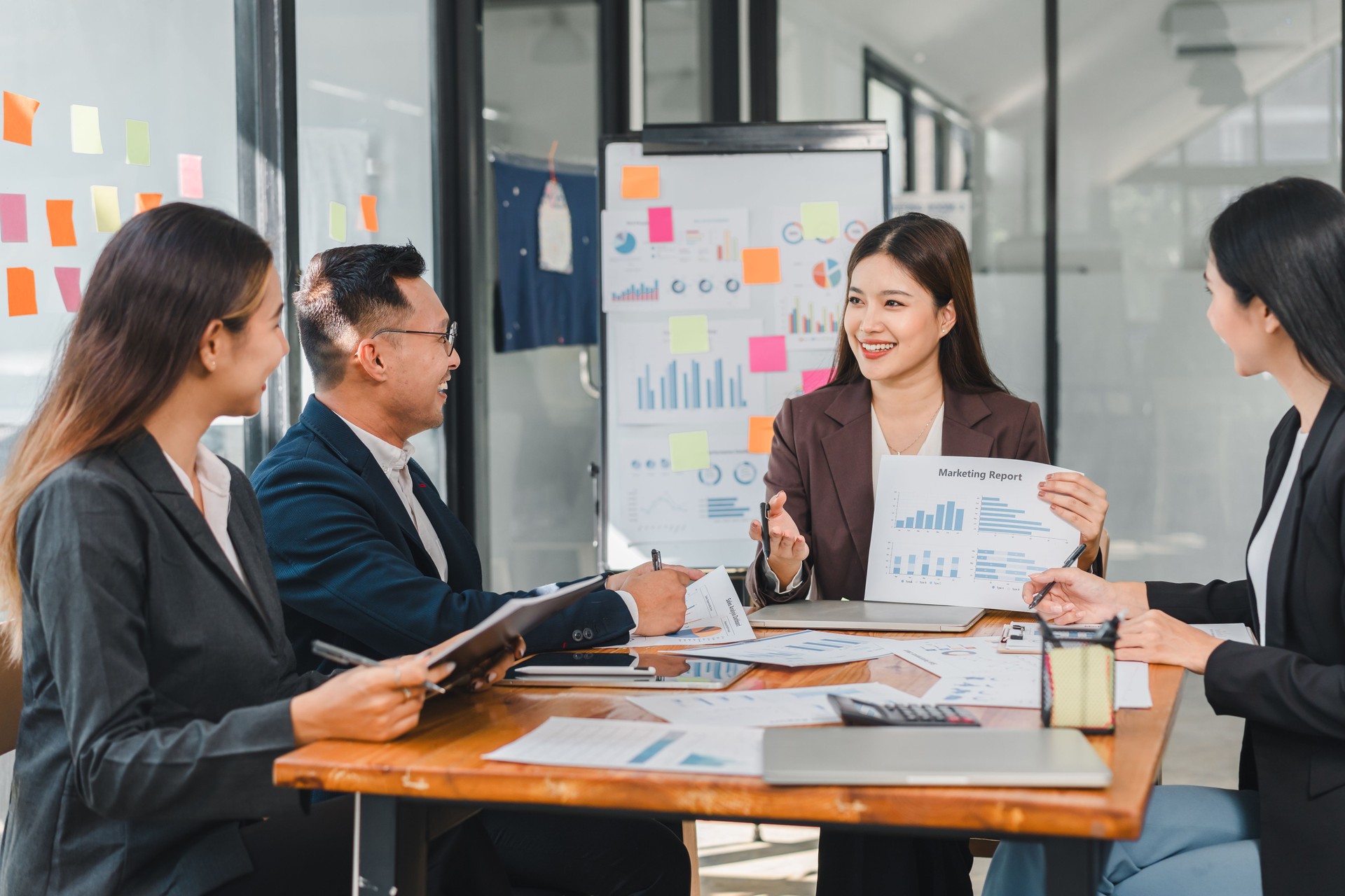 Professional team discussing marketing reports in modern office. They analyze data and collaborate on strategies, showcasing teamwork and communication